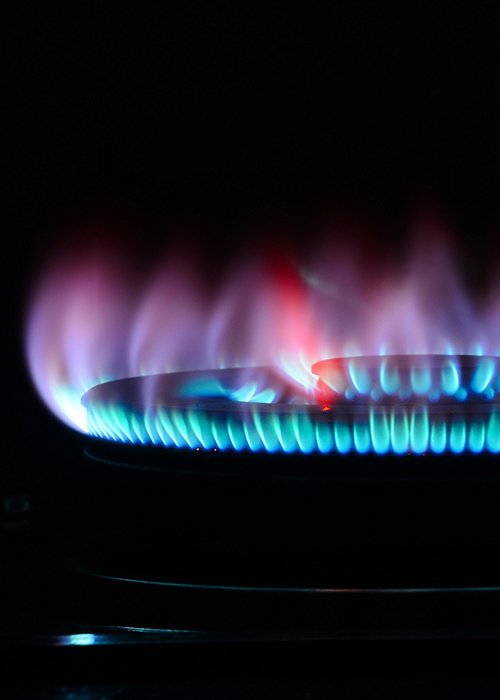 The blue flame of a cooker burner in the dark