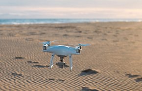 Aerial private drone lands at sand on beach