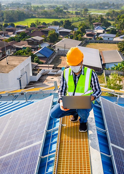 Engineers use a laptop computer to examine the solar panels on the roof of a house where the solar panels are installed using solar energy.