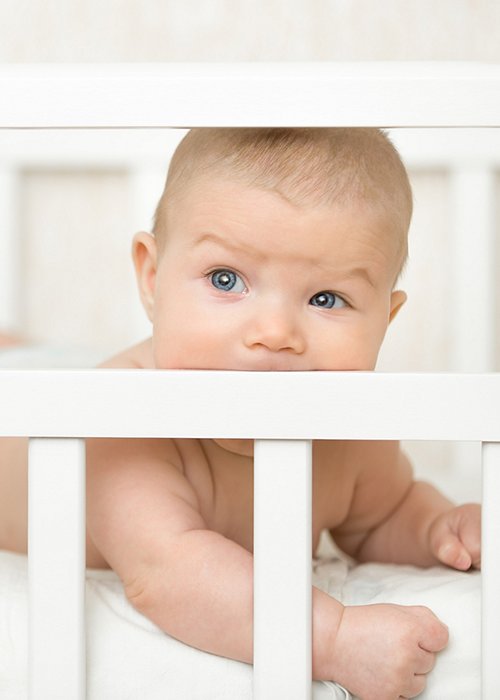 Cute baby in a cot sucking the wooden board Cute baby in a cot sucking the wooden board