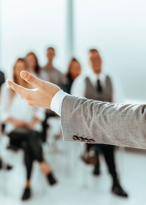 background image of a speaker standing in front of listeners in a conference room background image of a speaker standing in front of listeners in a conference room