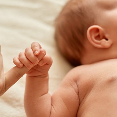 Faceless mother with naked baby, infant holding mommy's finger, mum spending time with her tiny child on light background. Faceless mother with naked baby, infant holding mommy's finger, mum spending time with her tiny child on light background.