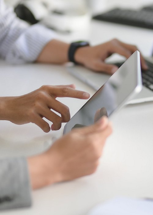 Young professional UI web developer working on his project with laptop computer and tablet