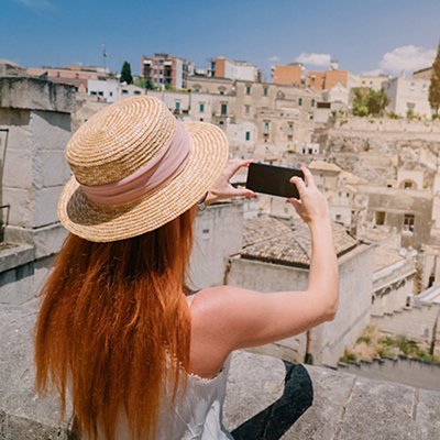 A young woman tourist photographs a panorama of an ancient European city.