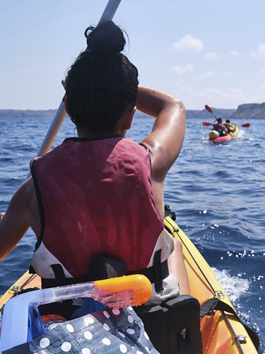 Faceless woman rowing kayak on sea