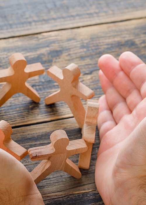 Business success concept on wooden background high angle view. hands protecting wooden figures of people. Business success concept on wooden background high angle view. hands protecting wooden figures of people.