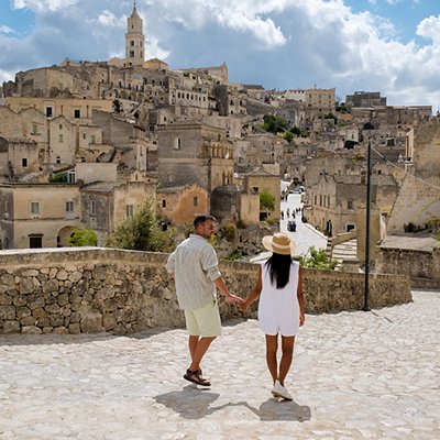 Couple exploring the enchanting streets of Matera, Puglia under a vibrant sky