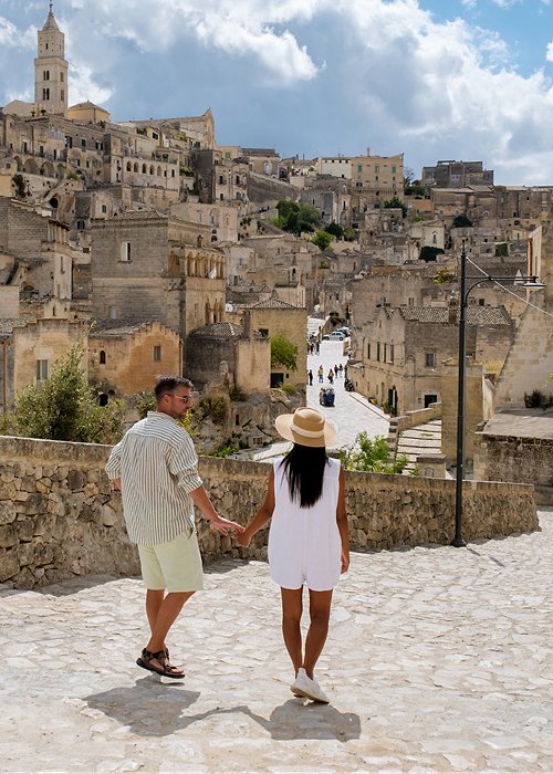 Couple exploring the enchanting streets of Matera, Puglia under a vibrant sky