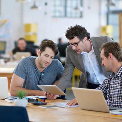 Shot of business colleagues discussing matters with the help of wireless technology in their office