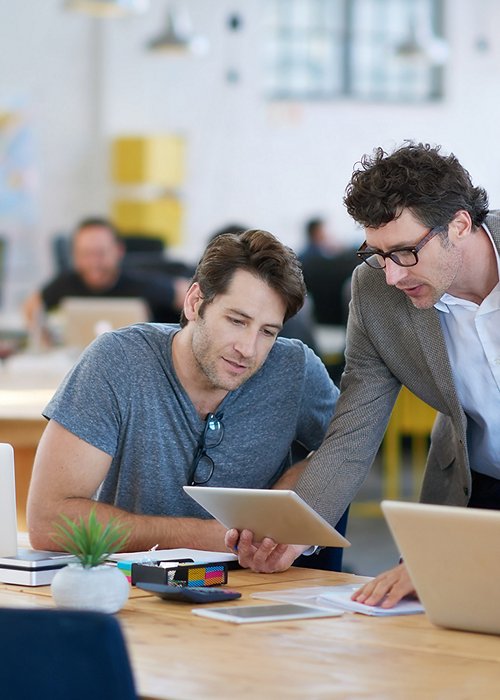 Shot of business colleagues discussing matters with the help of wireless technology in their office