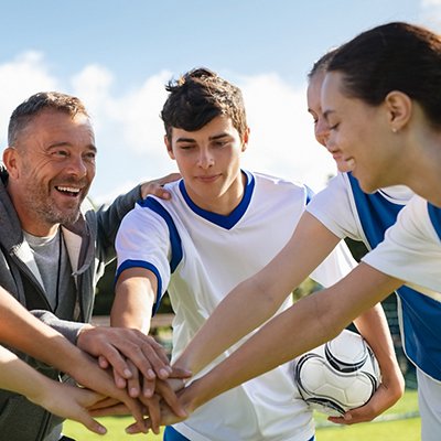 Team of young football players stacking hands before match