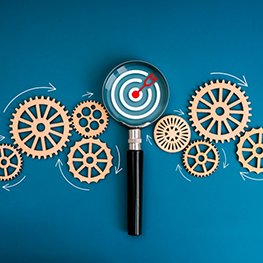 Business marketing trends, target workflow, teamwork management, market research management tool concept. Dartboard icon focus in magnifying glass with flowing wooden gears on blue background. Business marketing trends, target workflow, teamwork management, market research management tool concept. Dartboard icon focus in magnifying glass with flowing wooden gears on blue background.