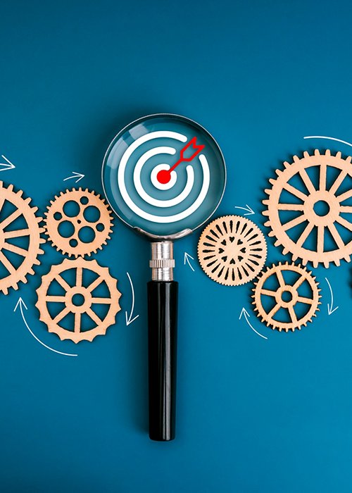 Business marketing trends, target workflow, teamwork management, market research management tool concept. Dartboard icon focus in magnifying glass with flowing wooden gears on blue background.
