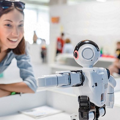 A female student controls the work of an intelligent humanoid robot A female student controls the work of an intelligent humanoid robot