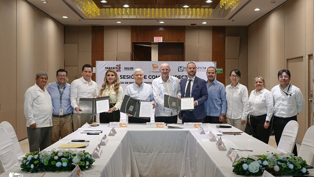 A group of people pose with some documents around a table