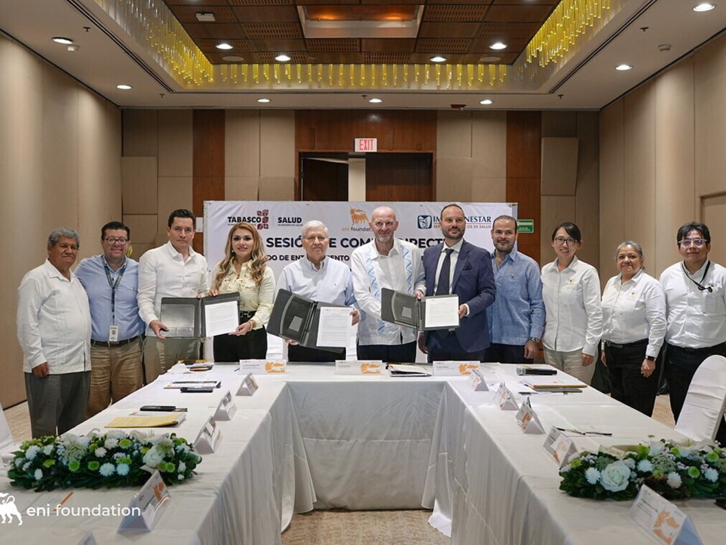 A group of people pose with some documents around a table