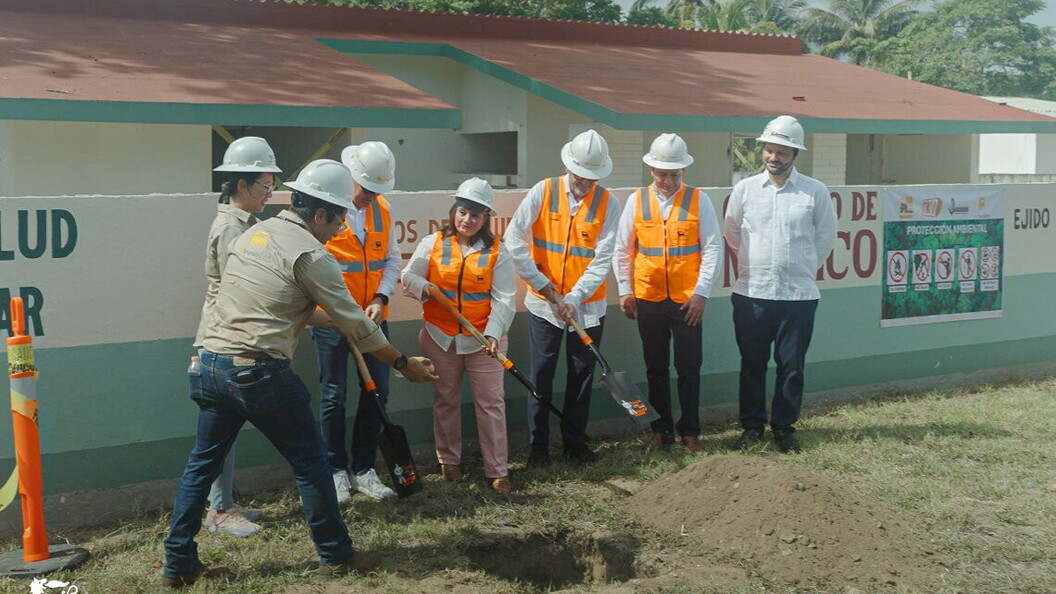 A group of people wearing helmets and orange jackets are working on an outdoor site