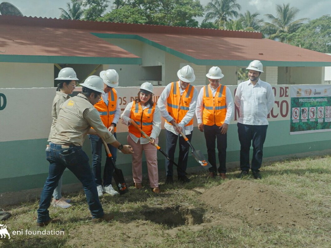 A group of people wearing helmets and orange jackets are working on an outdoor site