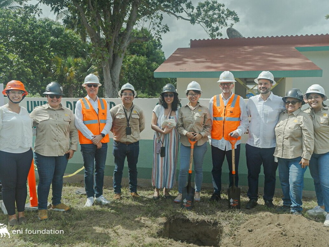 A group of people wearing helmets and orange jackets pose in front of a building