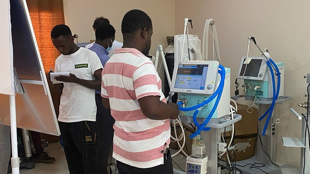 A group of people are focused on the operation of a monitor