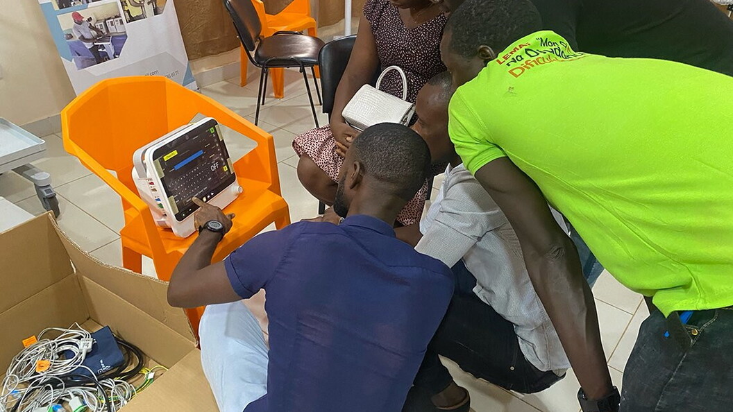 A group of people are focused on the operation of a monitor