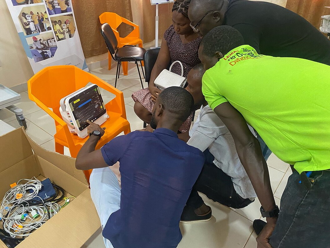 A group of people are focused on the operation of a monitor