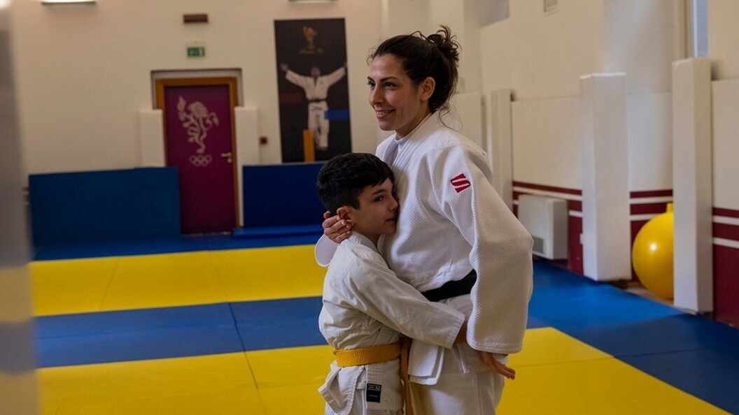 Un giovane allievo pratica arti marziali con il supporto dell’istruttrice
