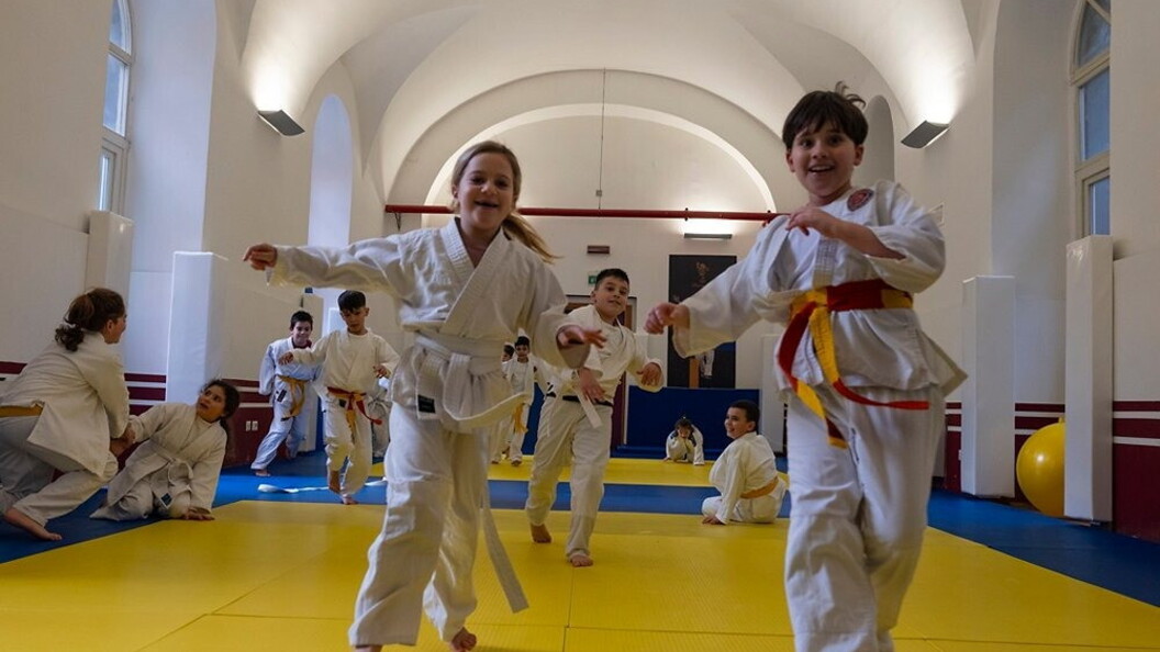 Bambine e bambini praticano arti marziali all'interno di una palestra