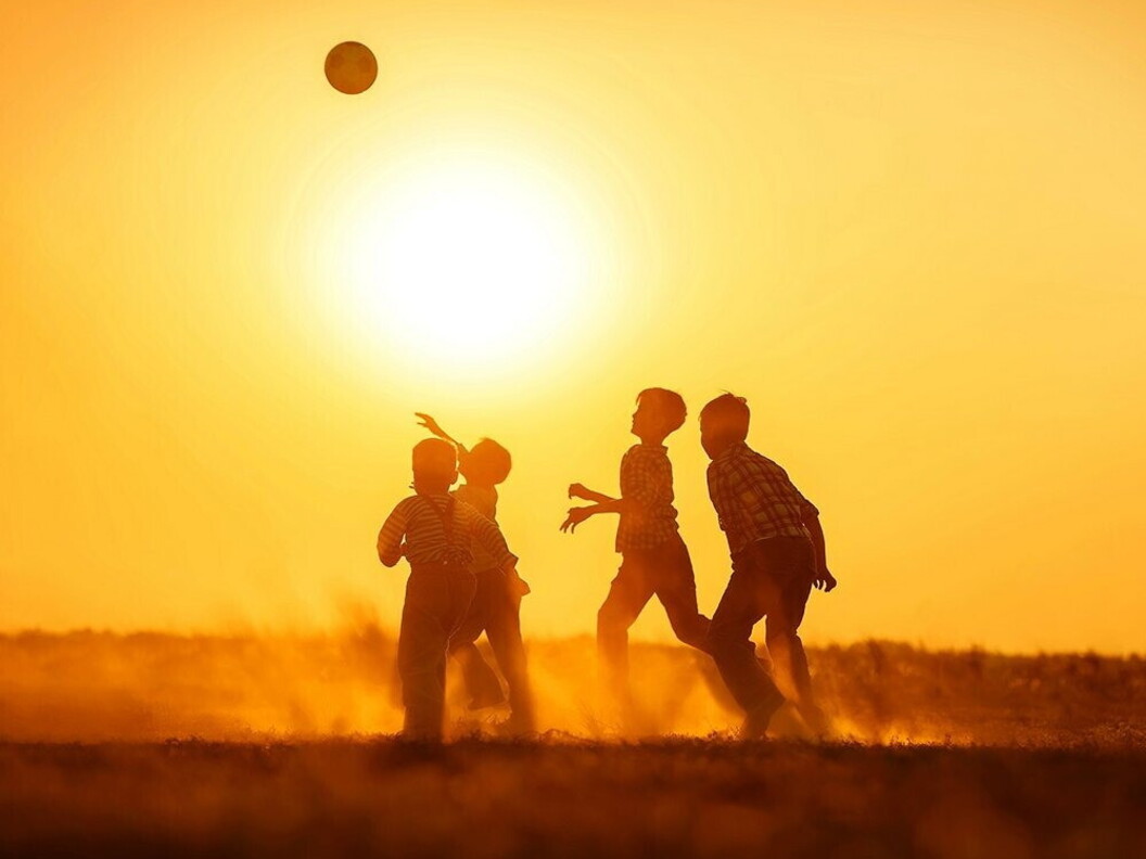 Alcuni ragazzi giocano a calcio al tramonto