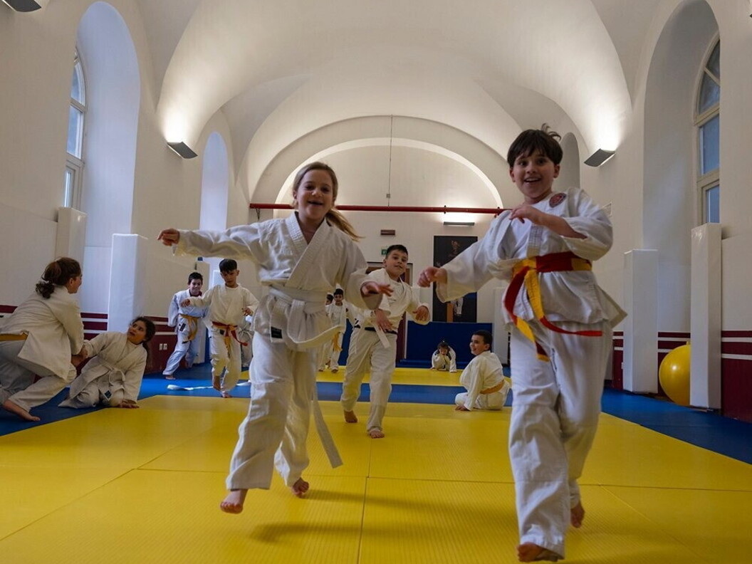 Bambine e bambini praticano arti marziali all'interno di una palestra