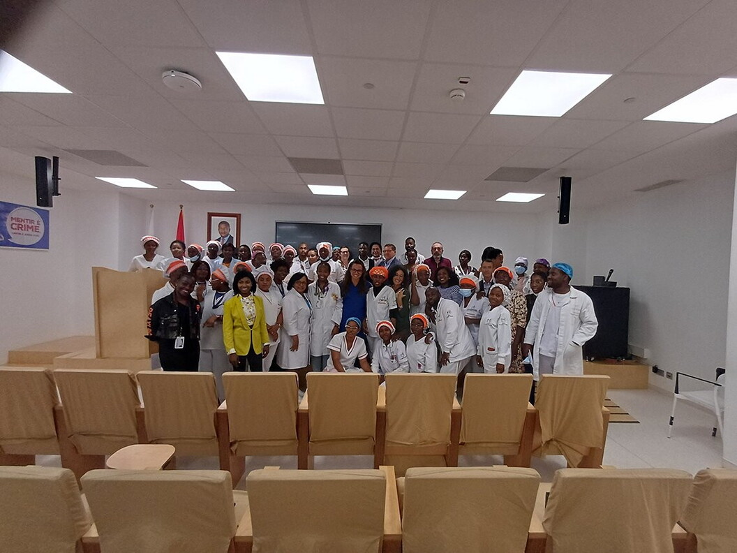 A group of people pose for a photo standing in a classroom.