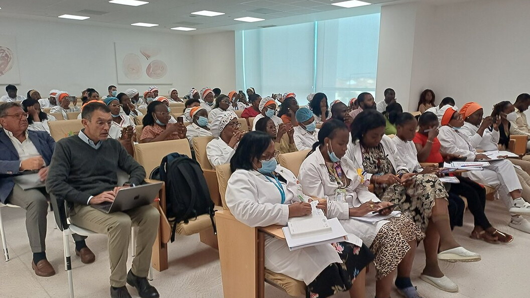 A group of men and women are sitting in a classroom and attending a meeting