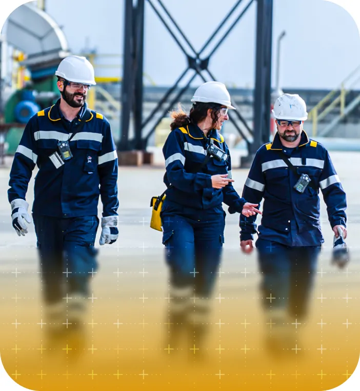 Four people in blue work suits and white safety helmets walking.