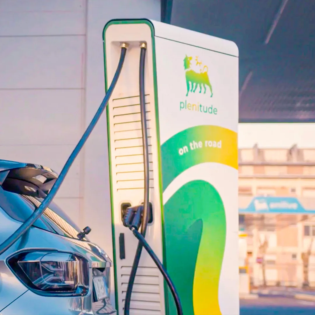 A person refuelling their car via an electric charging station at an Enilive station.