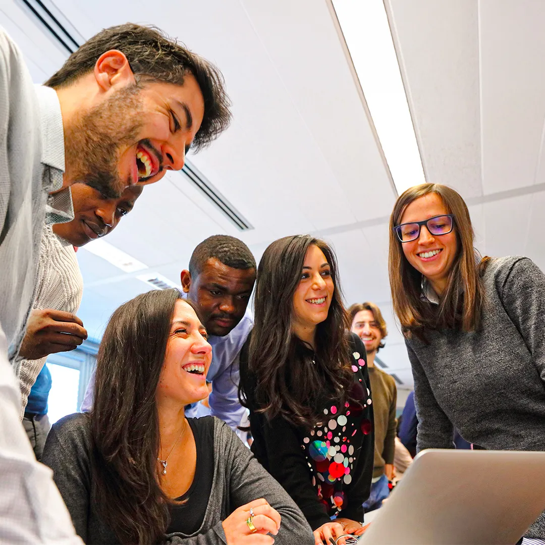Group of people laughing looking at a PC screen.