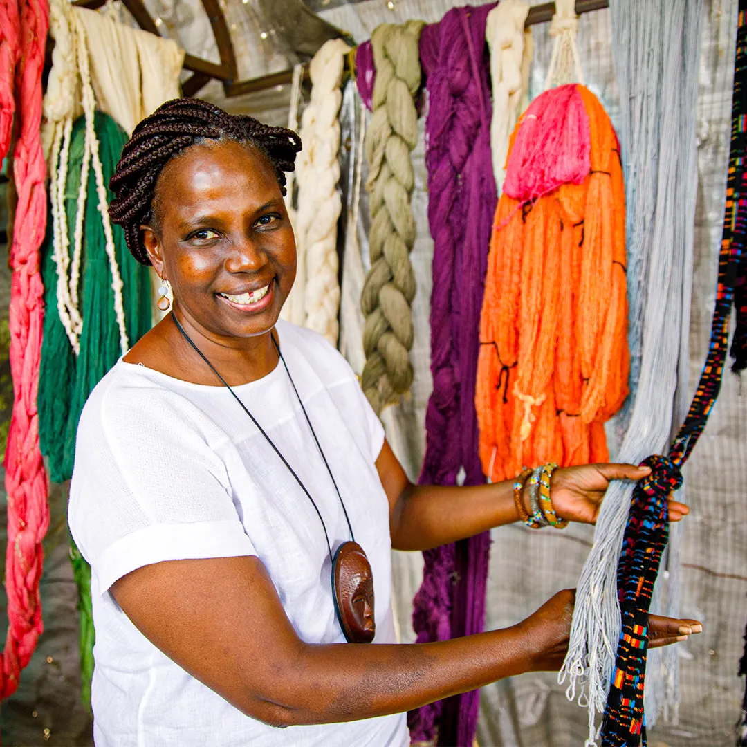 Smiling woman showing hanging fabrics.